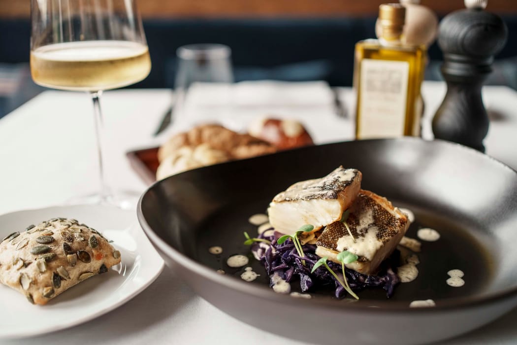 Detail of a fish dish served with a glass of wine