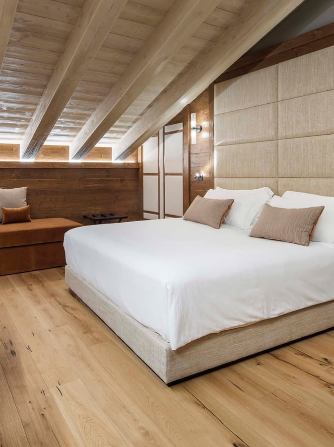 Dettaglio letto matrimoniale e soffitto con travi a vista  Deluxe Tripla